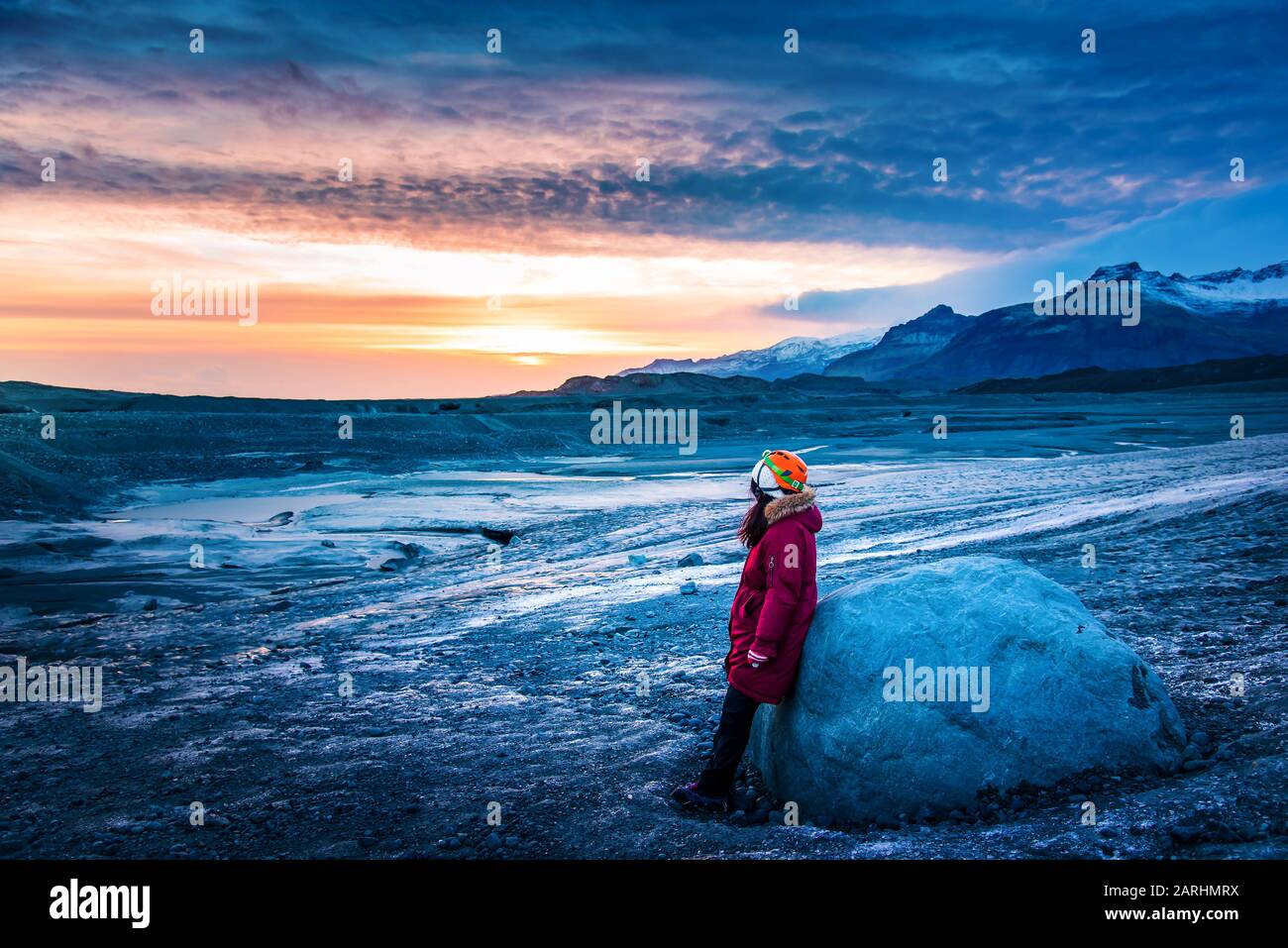 Woman walking on an Icelandic glacier ice surface and enjoying beautiful sunset Stock Photo