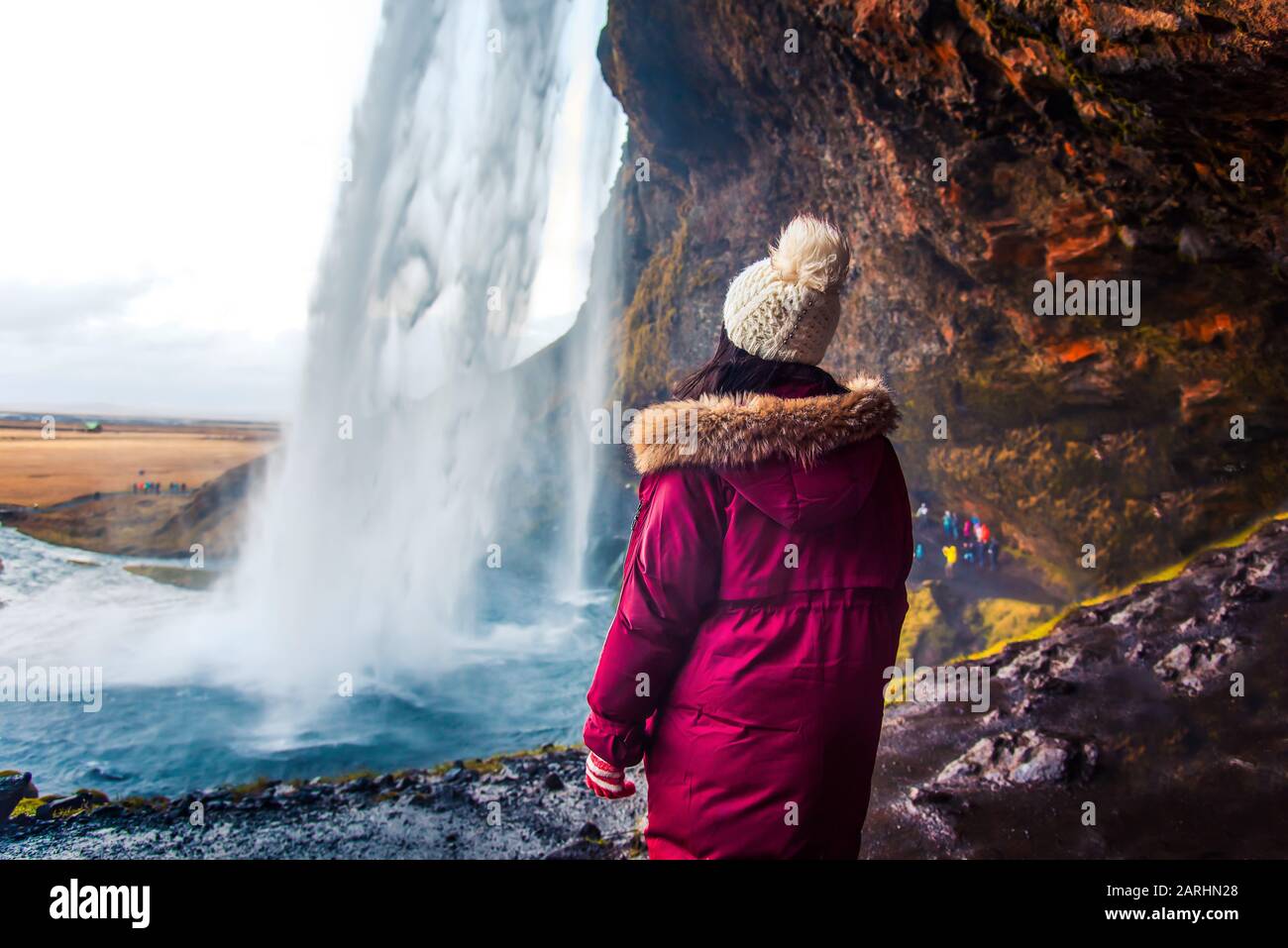 Woman enjoying visiting Seljalandsfoss waterfall view in Iceland on Icelandic roadtrip Stock Photo