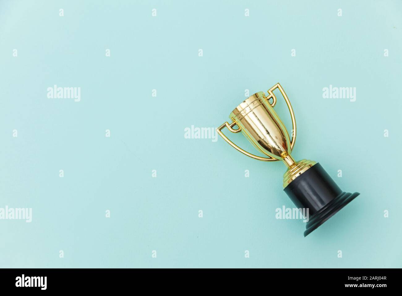 Simply flat lay design winner or champion gold trophy cup isolated on blue pastel colorful background. Victory first place of competition. Winning or success concept. Top view copy space Stock Photo