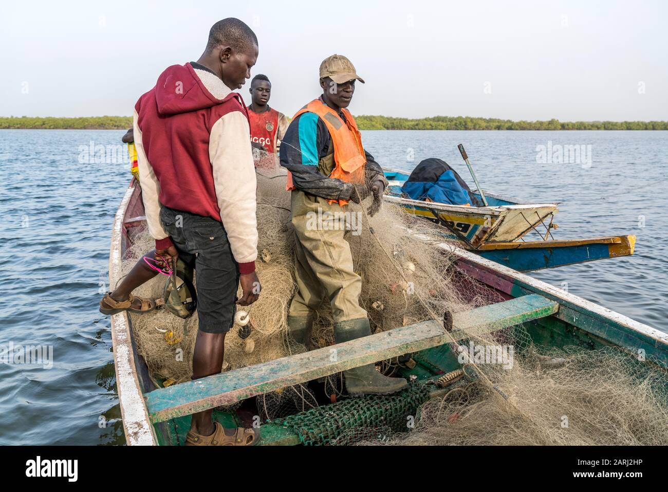 Fischer mit Netz in Ihrem Boot am Flussufer, Insel Jinack Island, Gambia,  Westafrika