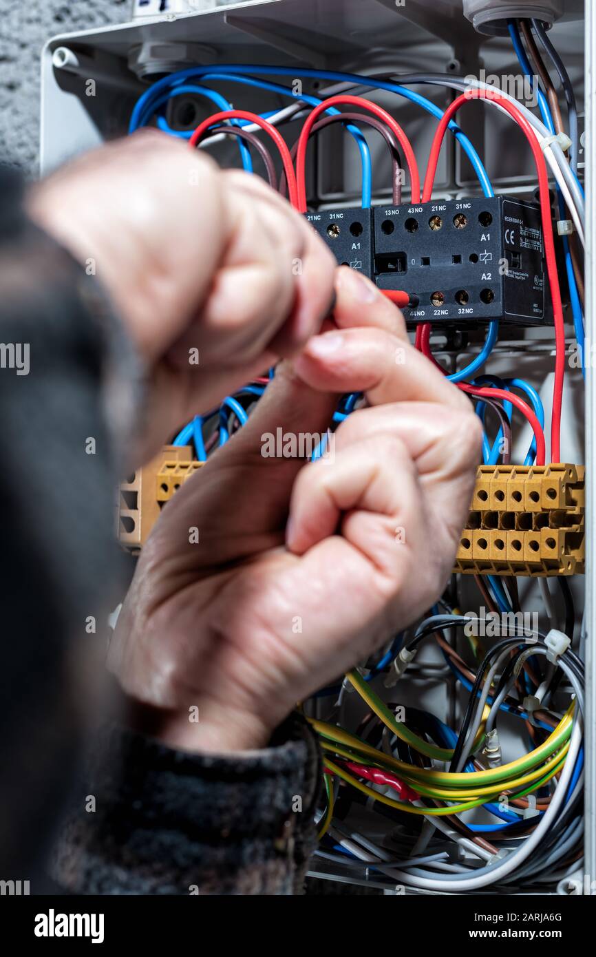 Electrician with screwdriver fixes the cable in a residential