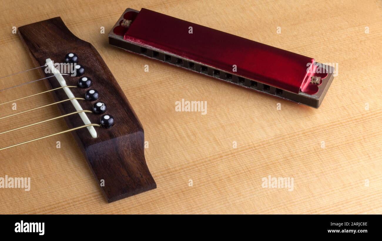 Old harmonica sitting on top of acoustic guitar Stock Photo