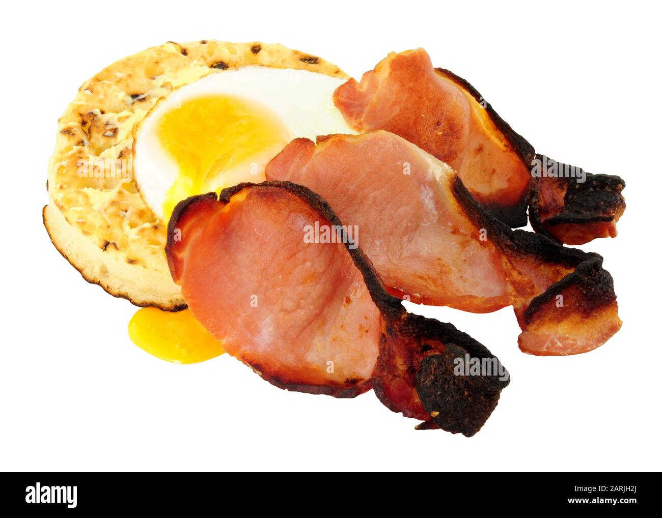 Fried egg and smoked bacon rashers on a large English crumpet isolated on a white background Stock Photo