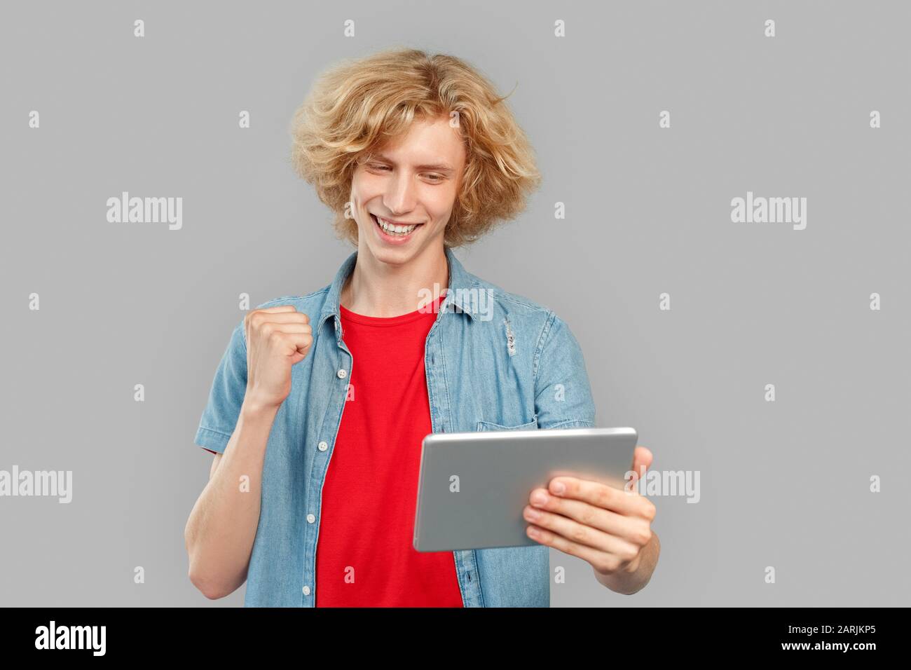 Young man using tablet computer and rejoiced Stock Photo