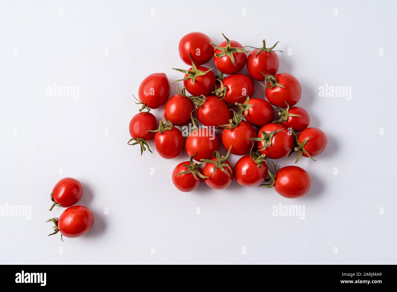 Small red ripe tomatoes pattern over white paper background. Stock Photo