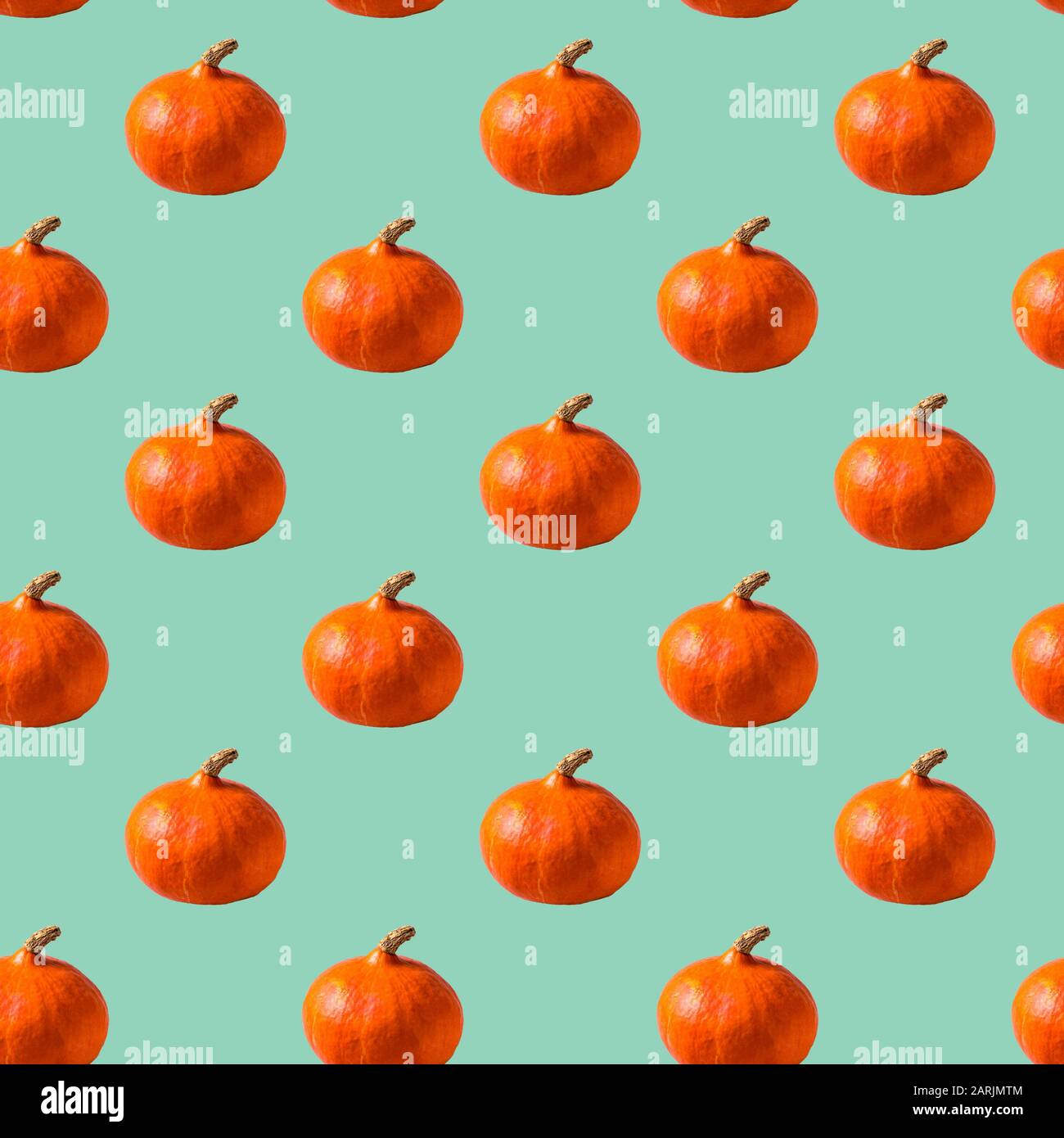 Flat lay Seamless Pattern made with orange pumpkin over neo mint background. Stock Photo