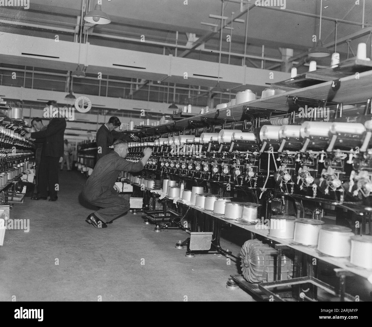 In the war-torn city of Arnhem, hard work is being done to build the art silk industry. This product so important for Dutch textile supply is manufactured here at the A.K.U. (Arnhem Kunstzijde Union). Spinning the yarns for shipping Annotation: Old number 902-1864 Date: 28 May 1947 Location: Arnhem Keywords: Industry, Textile Industry Stock Photo