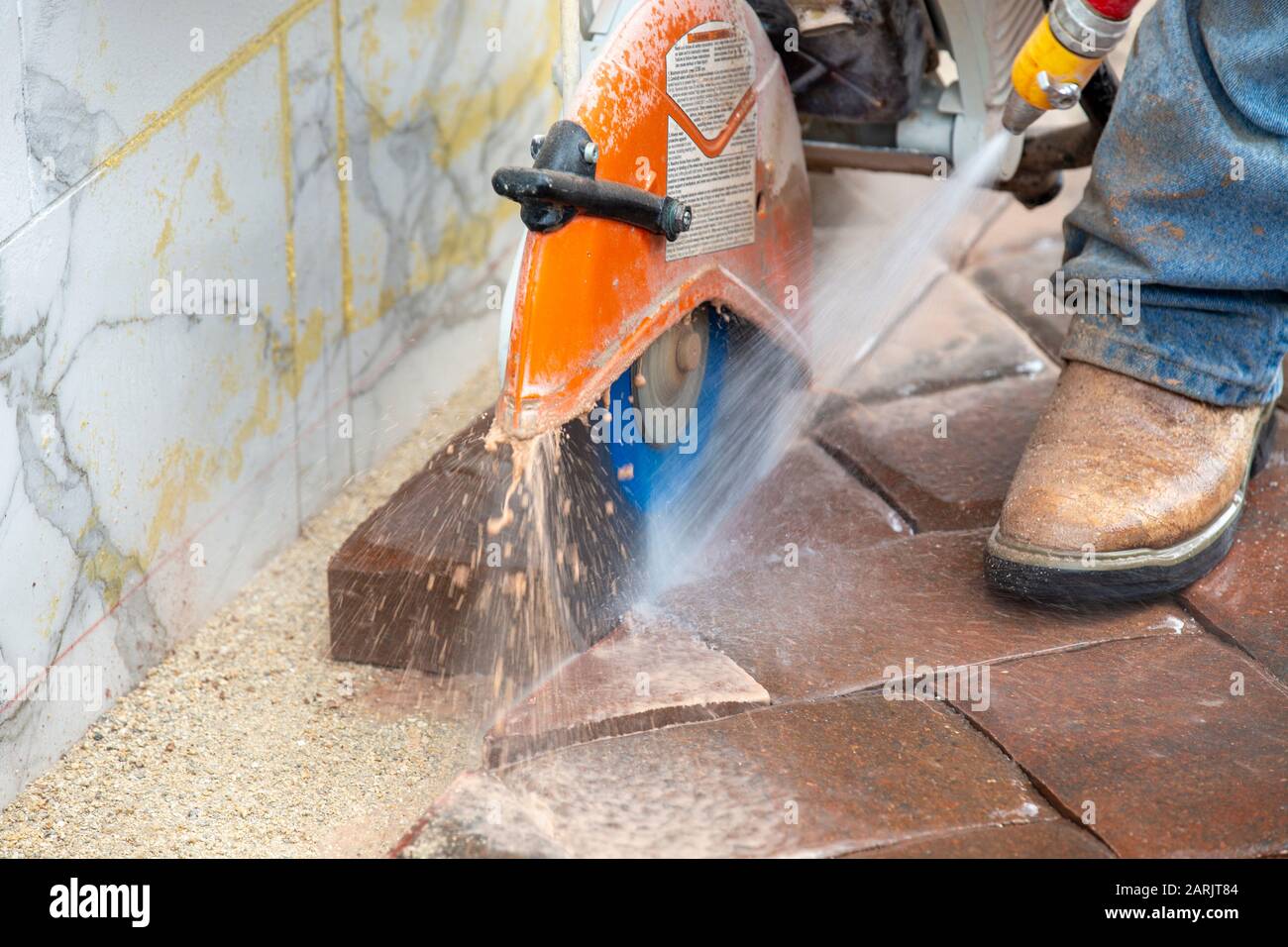 Construction worker sawing paving bricks in a straight line for a precision Paving job. Wetsaw Stock Photo