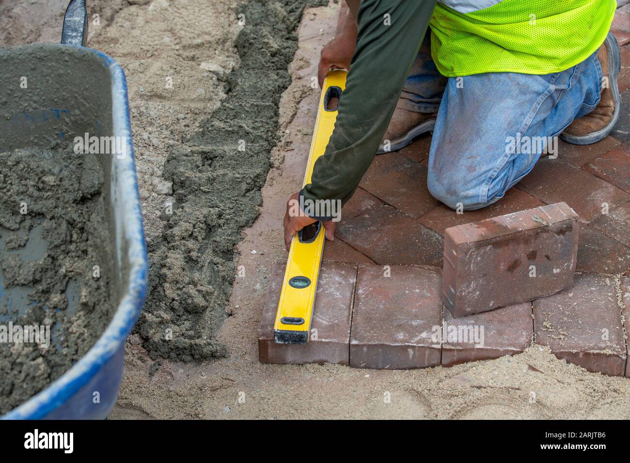 Brick layer or paver measuring and using a level to insure that his