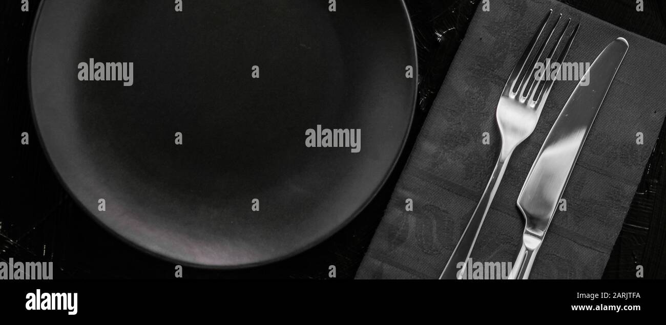 Dishware, menu and table concept Empty tableware with black napkin