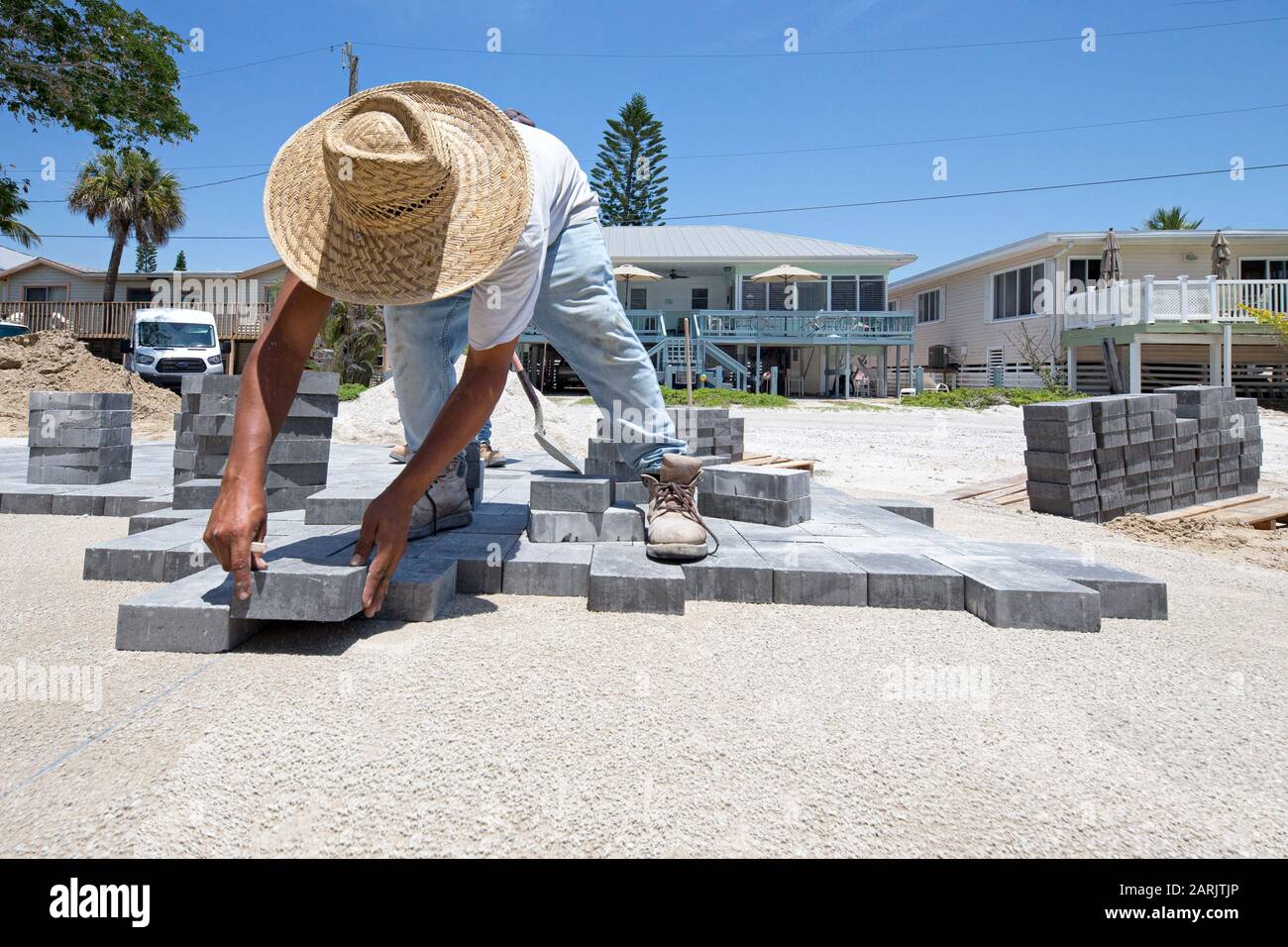man, laborer laying down paving bricks as he is paving a driveway Stock Photo