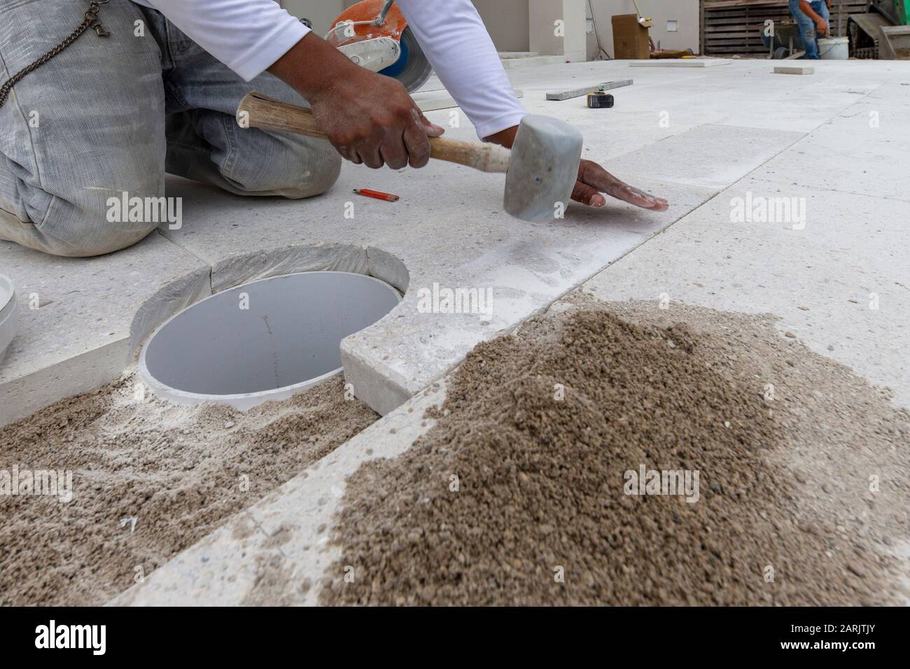 paver tapping or tamping on a granite concrete tile and setting it in