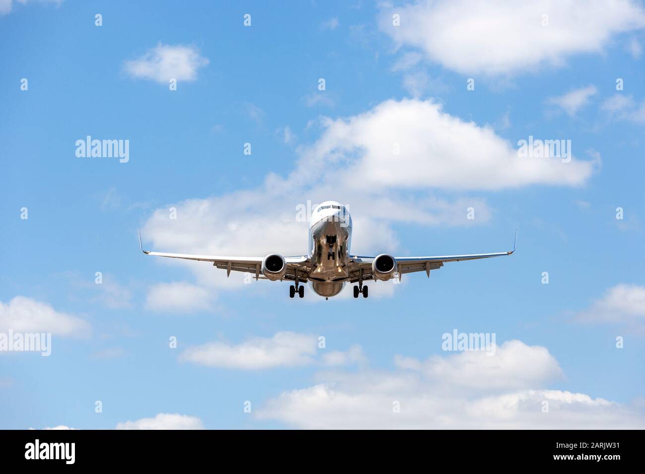 Boeing 737 landing. Front view with extended flaps, landing gear down and lights on. The wings have extended wingtips. Stock Photo