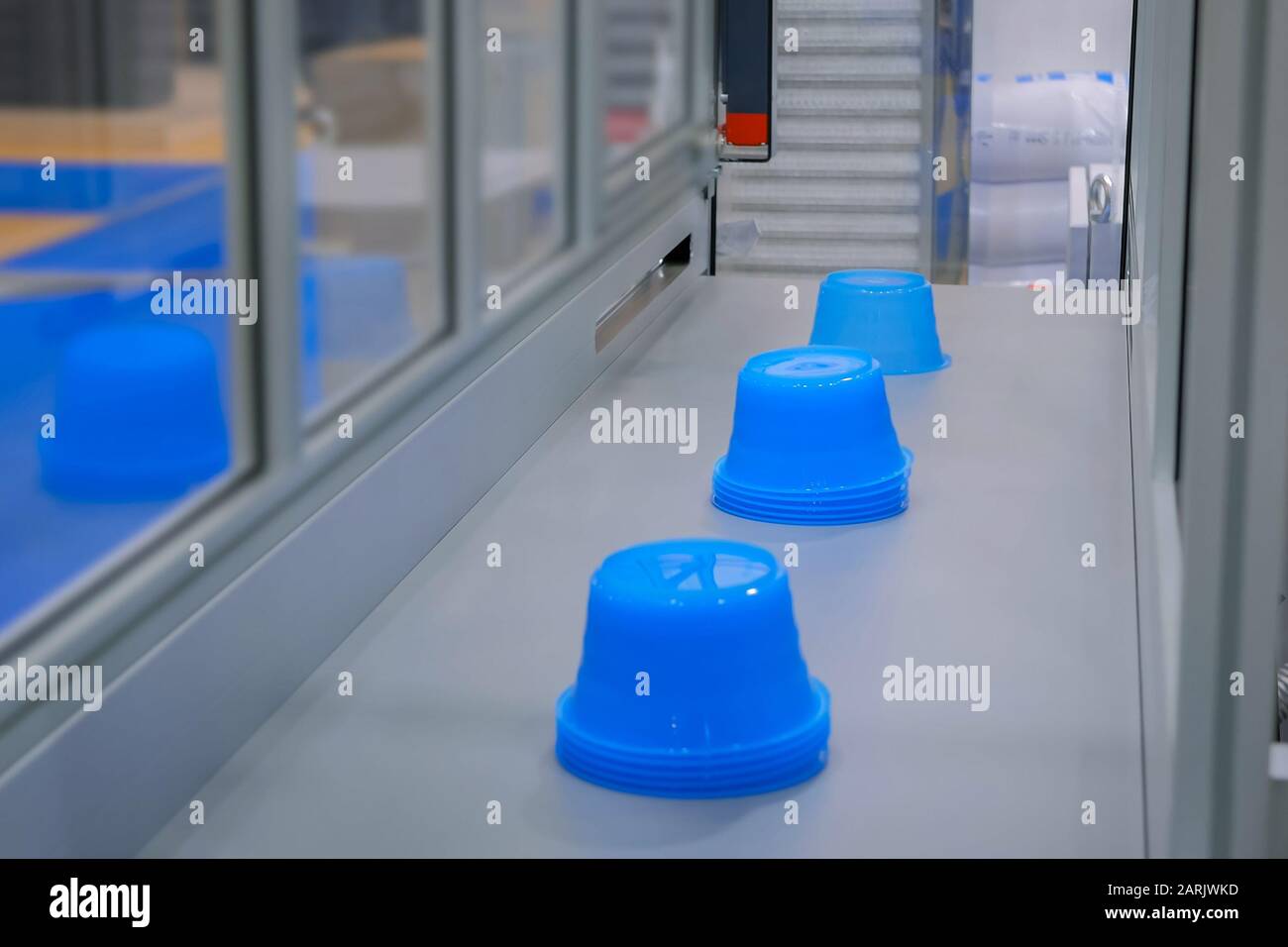 Blue pots on conveyor belt of plastic injection molding machine at exhibition Stock Photo