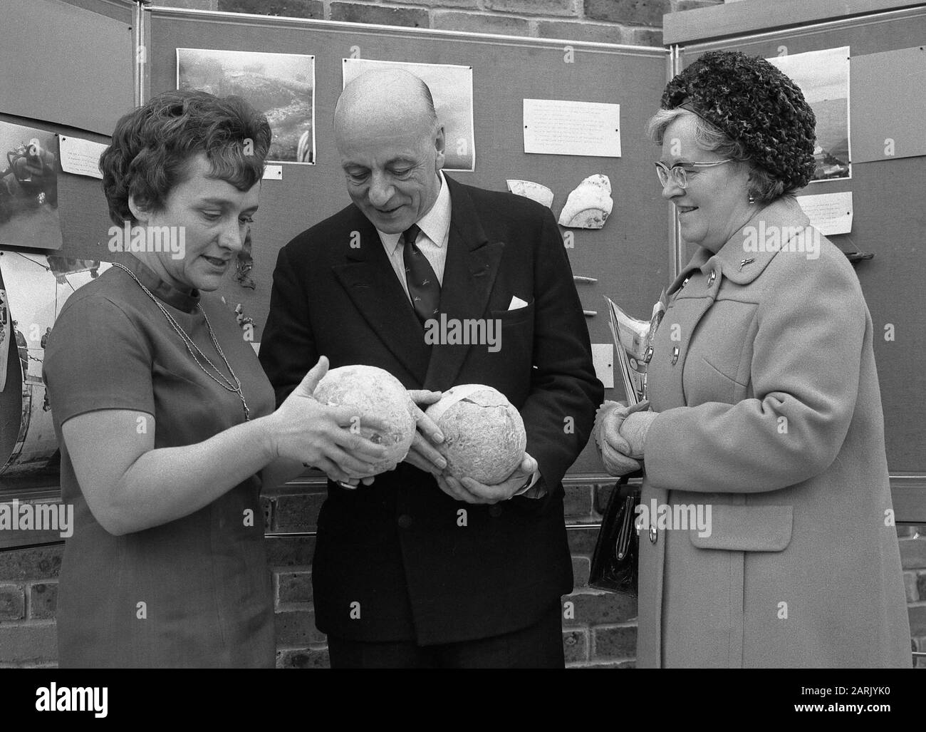 AJAXNETPHOTO. 17TH NOVEMBER, 1971. FISHBOURNE, ENGLAND. - RULE AND ROSE INSPECT BALLS. - SIR ALEC ROSE WHO SAILED AROUND THE WORLD SINGLE HANDED IN 1967-8 IN A 36FT KETCH CALLED LIVELY LADY (CENTRE) WITH HIS WIFE LADY ROSE (RIGHT) AND TUDOR SHIPWRECK MARY ROSE ACHAEOLOGIST AND RECOVERY PROJECT LEADER MARGARET RULE (LEFT) EXAMINE CANNON BALLS RECOVERED FROM THE WRECK SITE AT A PRESS CONFERENCE HELD AT FISHBOURNE'S ROMAN PALACE.  PHOTO:AJAX NEWS & FEATURE SERVICE REF:711117 10 8 Stock Photo