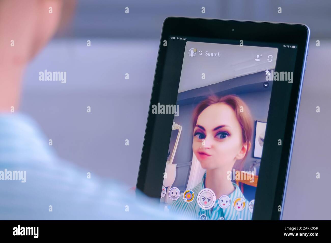 Woman using Snapchat multimedia messaging app with face mask on tablet Stock Photo