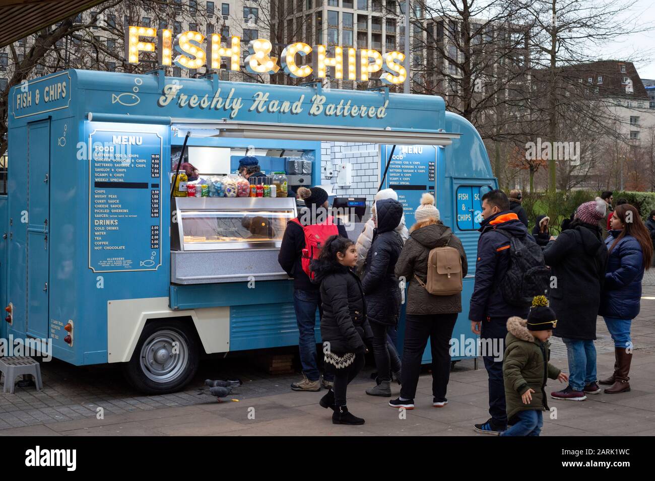 Street food London truck People and tourists queueing for fish and chips at a vintage style blue van as a mobile food stall on the South Bank in London, UK as of 2020 Stock Photo
