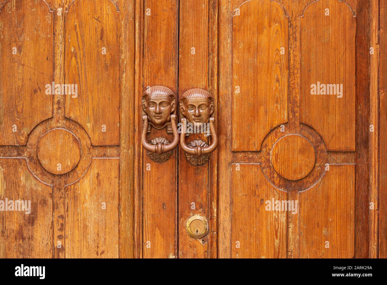 Italy, Sicily, Messina Province, Caronia. Egyptian styled knockers on wooden doors in the medieval hilltop town of Caronia. Stock Photo