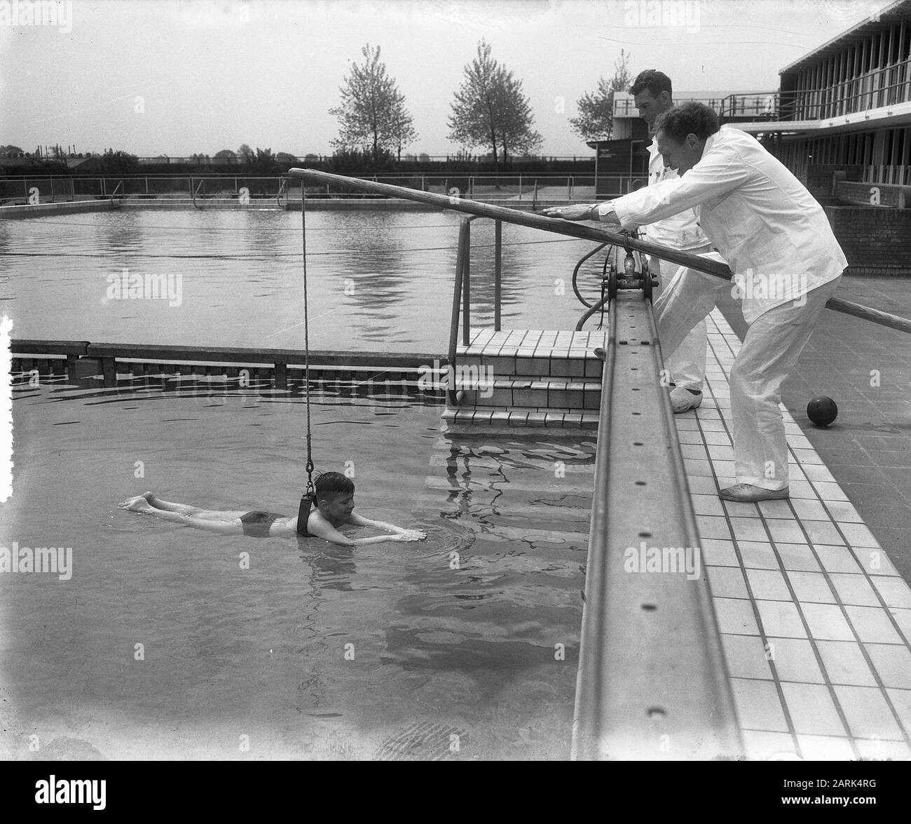 First student in Jan Van Galenbad (Rob Jansen, 8 years old). Lesson with the running rod Date: 17 May 1953 Location: Amsterdam, Noord-Holland Keywords: pupils, swimming pools, swimming lessons, swimming Person name: Jansen Rob Stock Photo