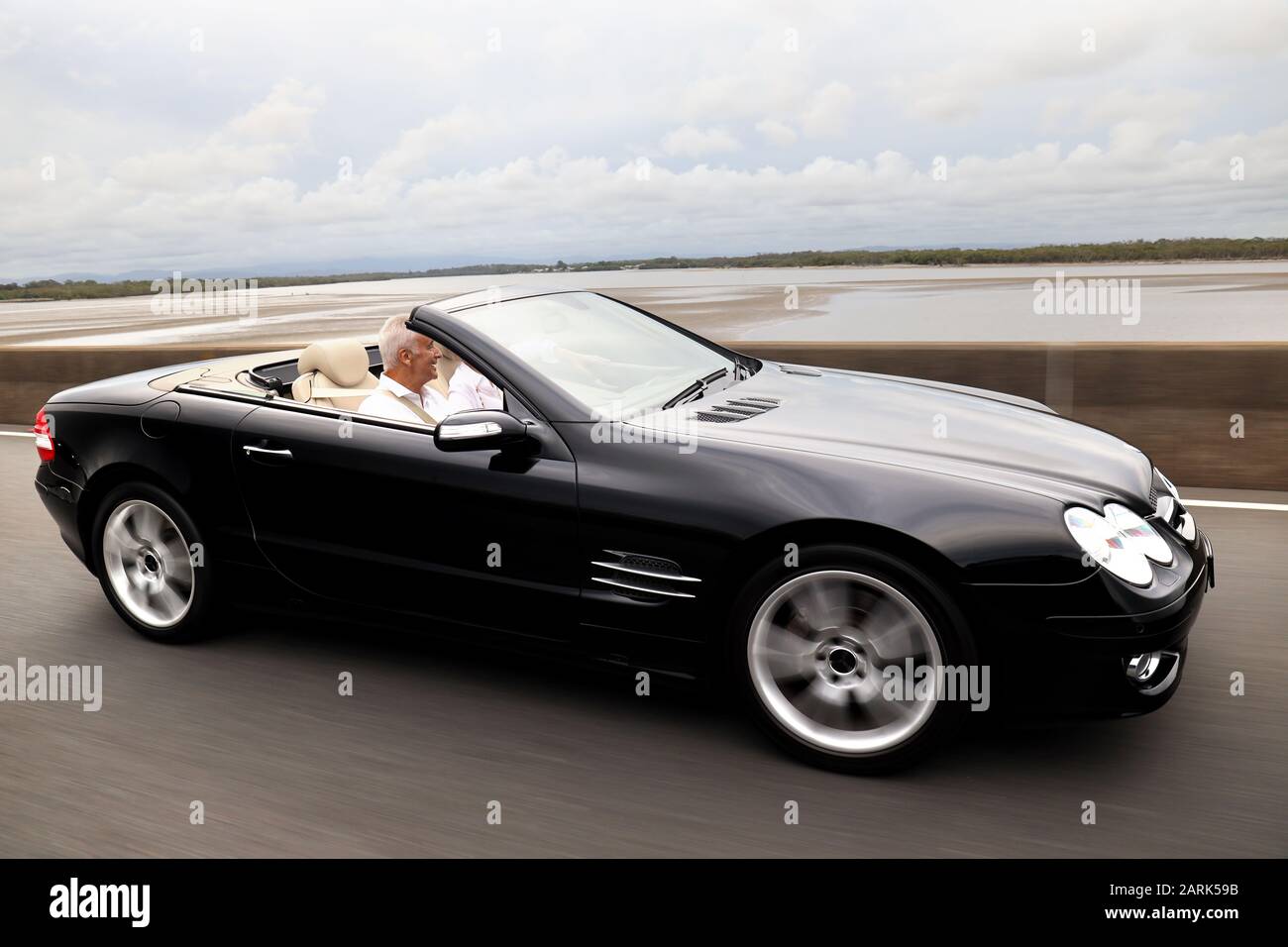 Mature married couple: A mature couple cruising along the road on a summer day with the top down in the black Benz convertible. Motion blur Stock Photo