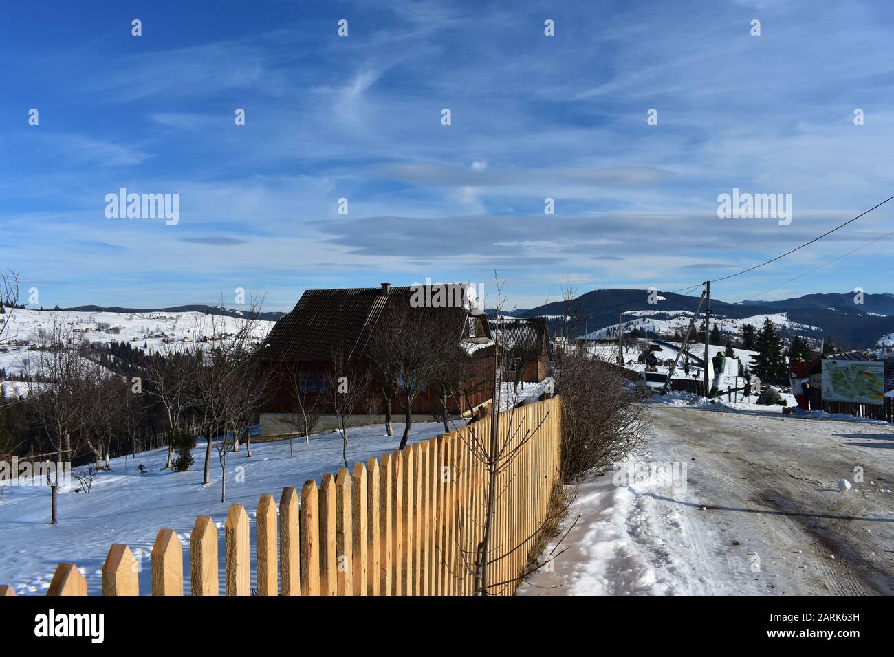 Ukraine Carpathians village fence and road in winter sunny day Stock Photo