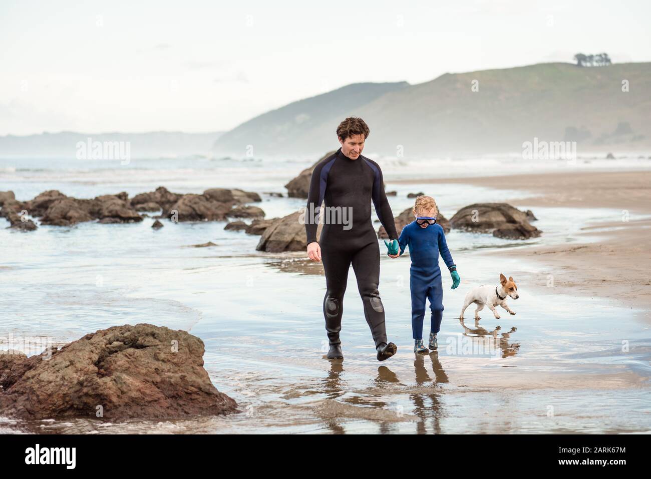 Father and young child holding hands at New Zealand beach Stock Photo