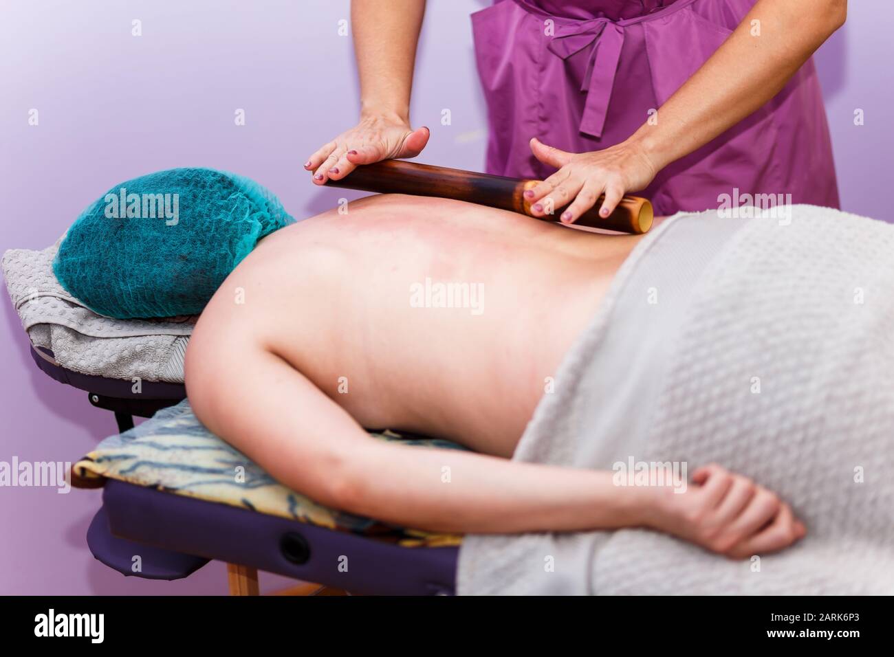 Professional massage therapist kneading back of client by spa roller Stock Photo