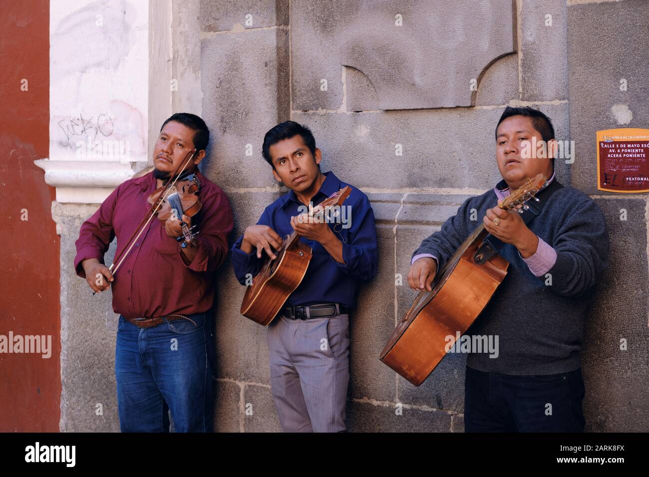 Three Mexican musicians playing string instruments against a wall in old town Puebla, Mexico. Stock Photo
