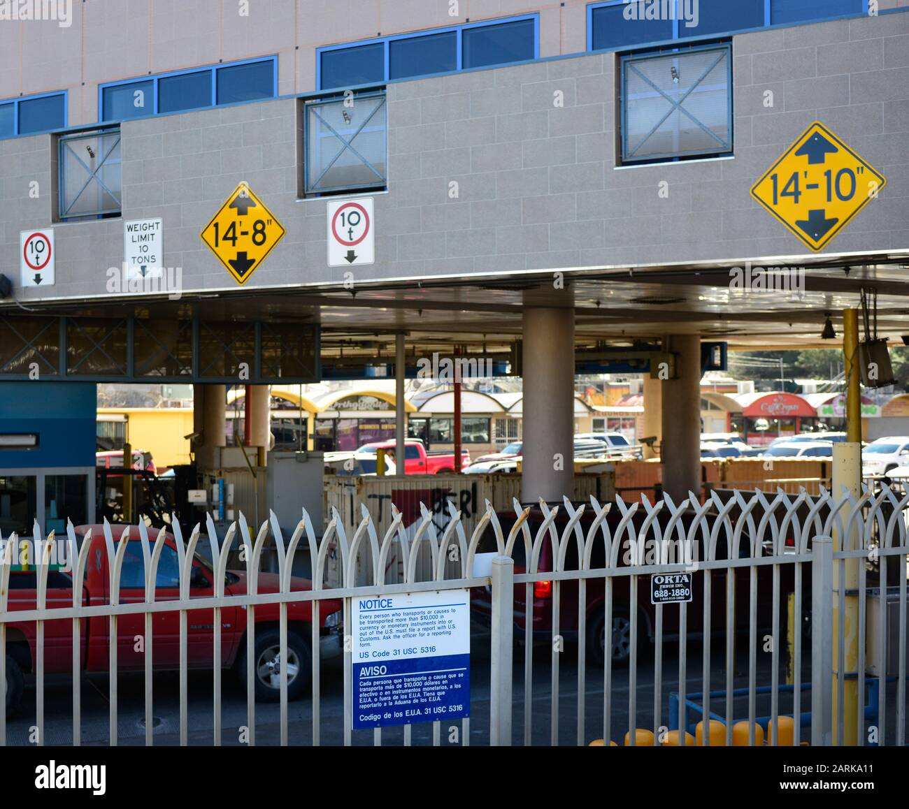 View of metal fence and cars crossing the border into the commercial district of Nogales, MX from Nogales, AZ, USA Stock Photo