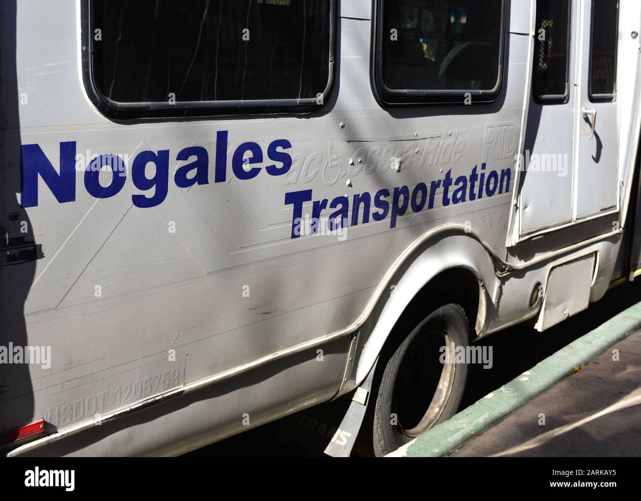 A white repainted and well worn small transport Bus with blue lettering reading Nogales Transportation, often used for cross Border transport, parked Stock Photo
