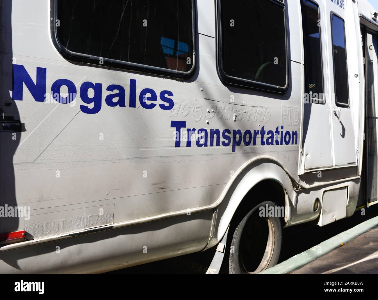 A white repainted and well worn small transport Bus with blue lettering reading Nogales Transportation, often used for cross Border transport, parked Stock Photo
