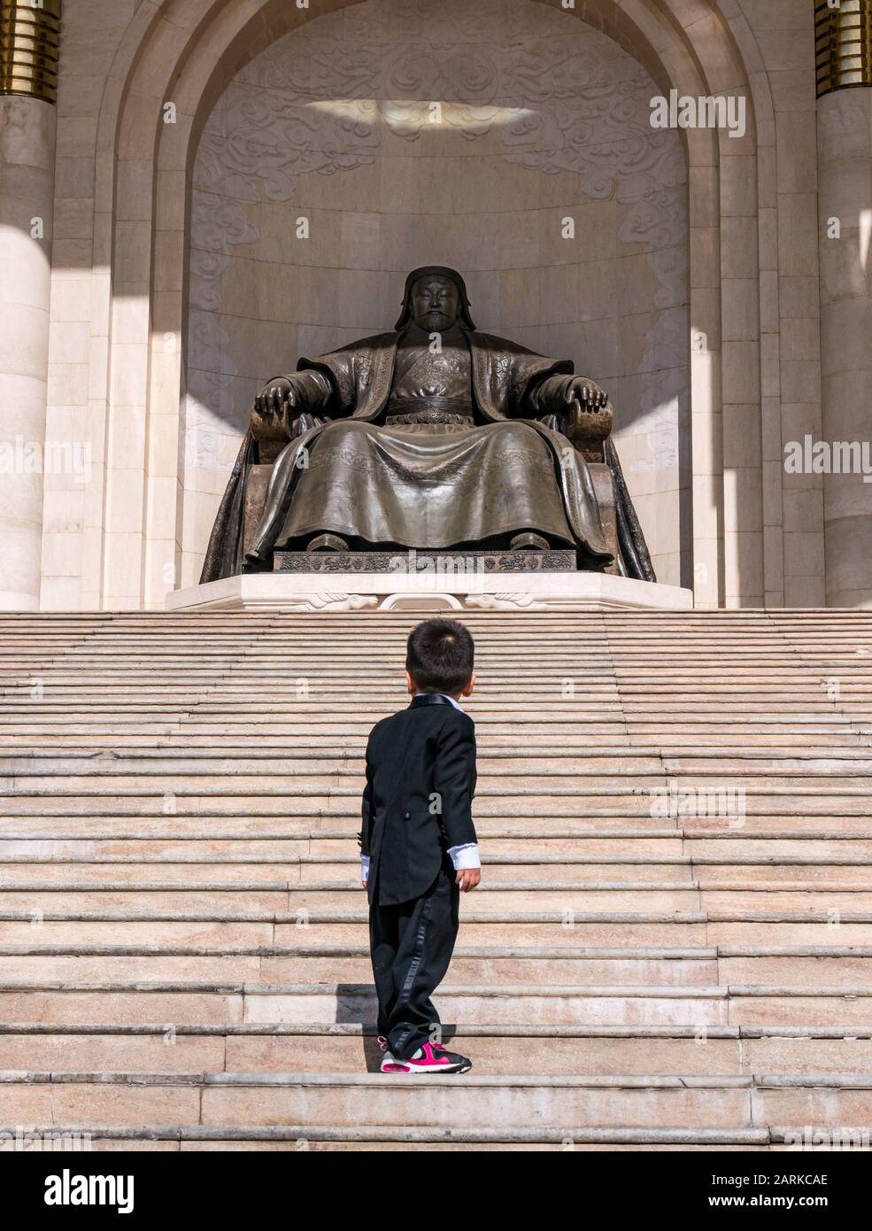 Young boy on steps looking at Genghis Khan statue, Government Place, Sükhbaatar Square, Ulaanbaatar, Mongolia Stock Photo
