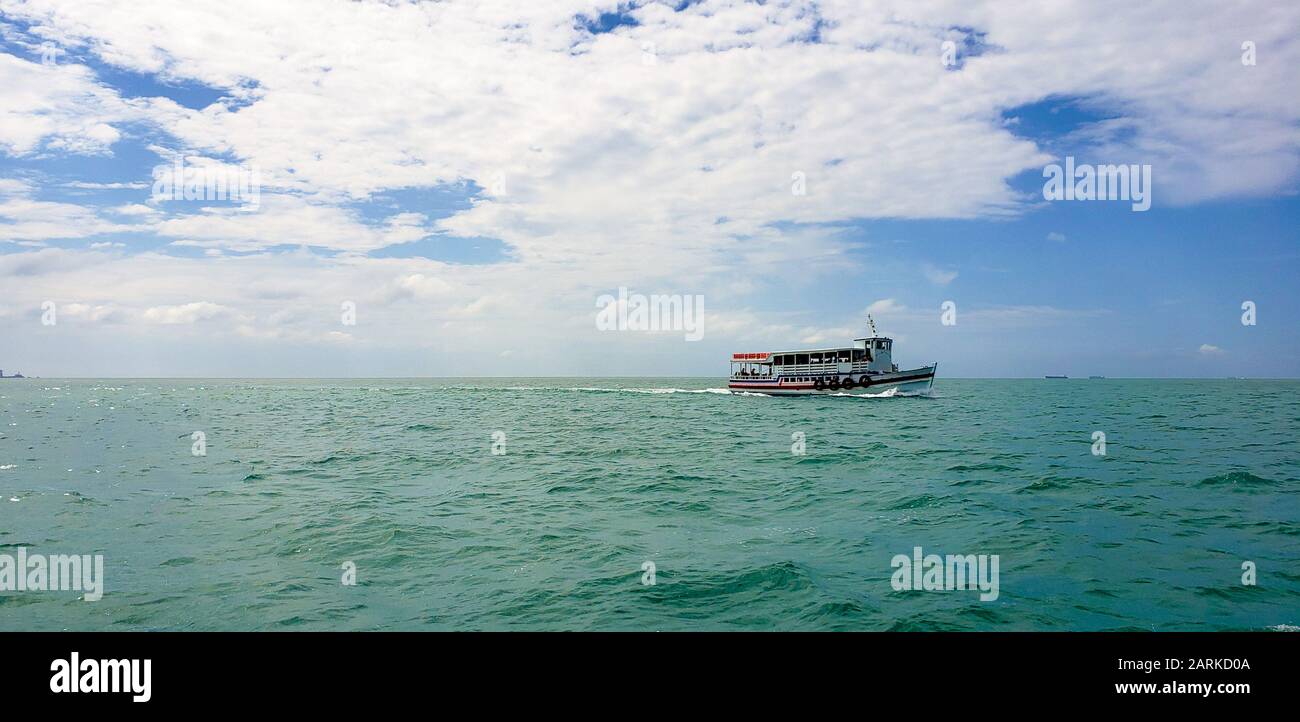 Boat crossing the ocean with intense green color and sky full of clouds. Crossing between Salvador and itaparica Stock Photo