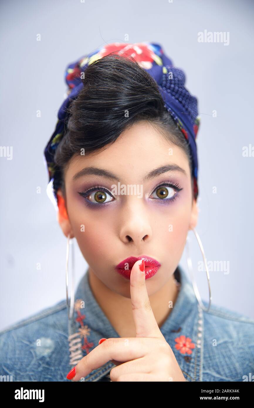 Funny girl isolated on a grey background joined the index finger to the lips Stock Photo