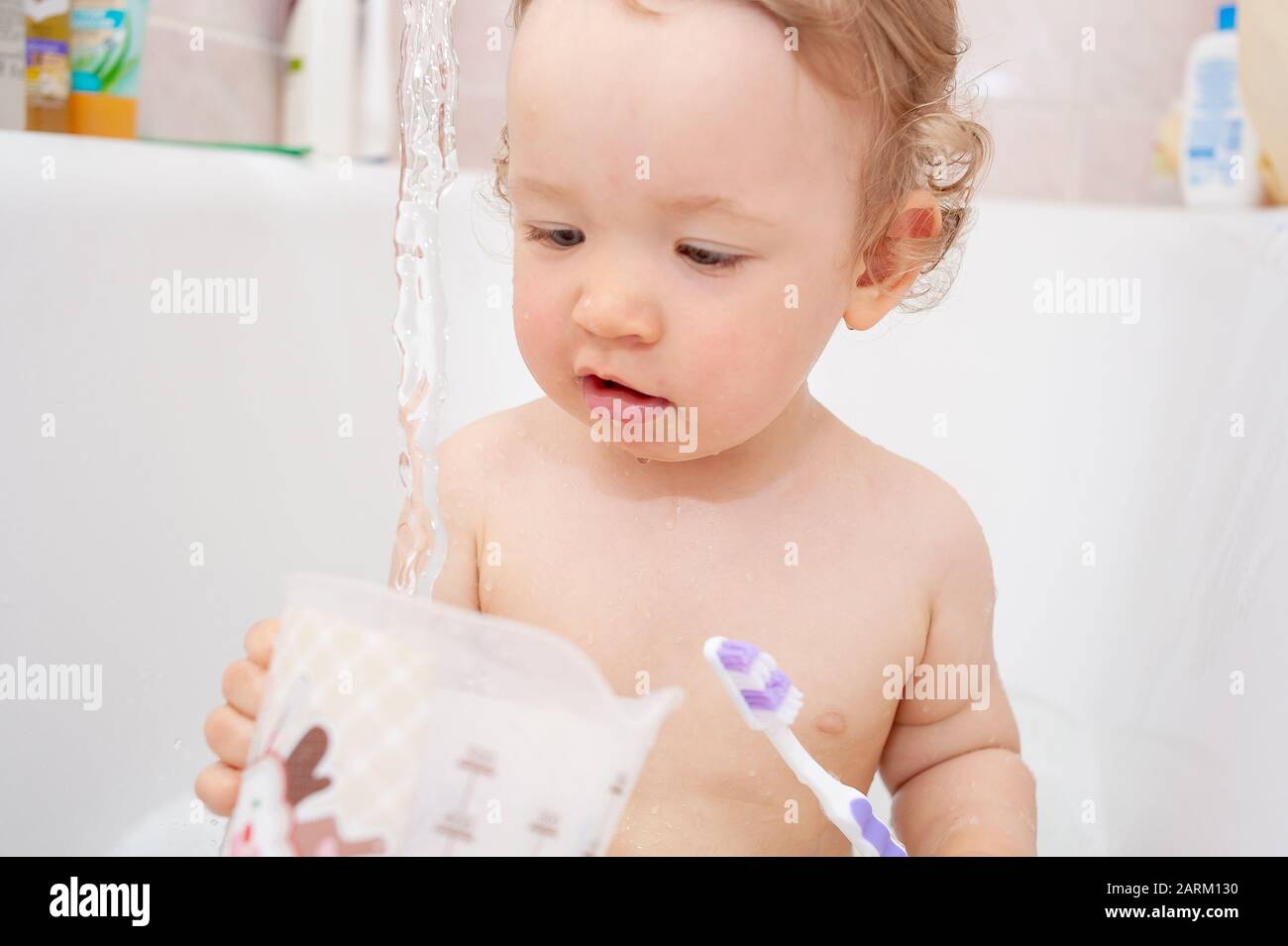 Funny happy baby with curly hair taking bath and brushing her teeth. A cute  baby girl is happy in the bathroom Stock Photo - Alamy