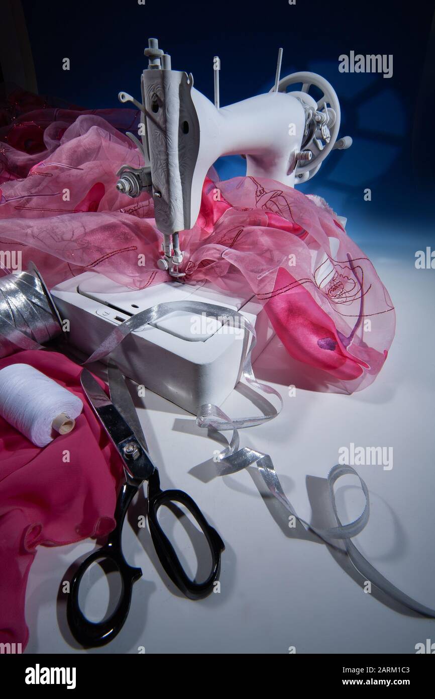 Sewing machine, fabric and scissors on a studio background Stock Photo