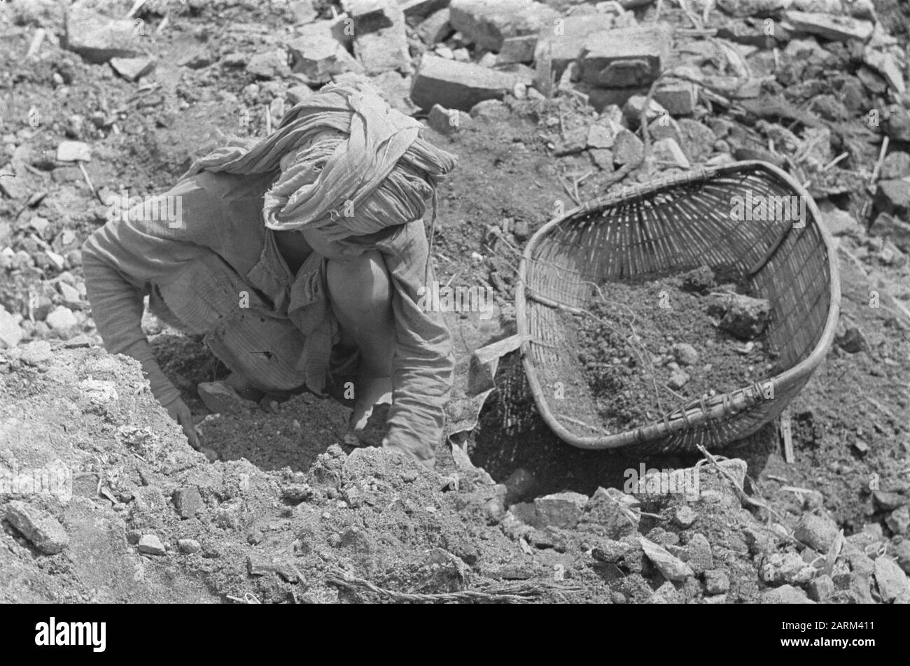 Photo Reportage Palembangs  Destroyed bank building. Debris is searched in search of remnants of coins or banknotes. Boy with headscarf Date: January 1947 Location: Indonesia, Dutch East Indies, Palembangs, Sumatra Stock Photo