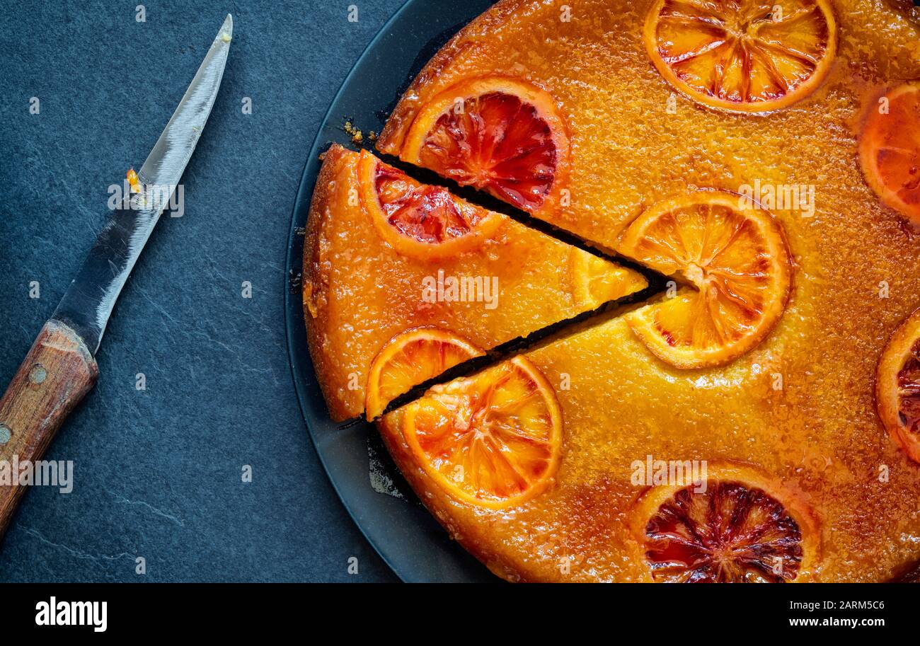 Homemade upside down blood orange cake with blood orange syrup on a slate background Stock Photo