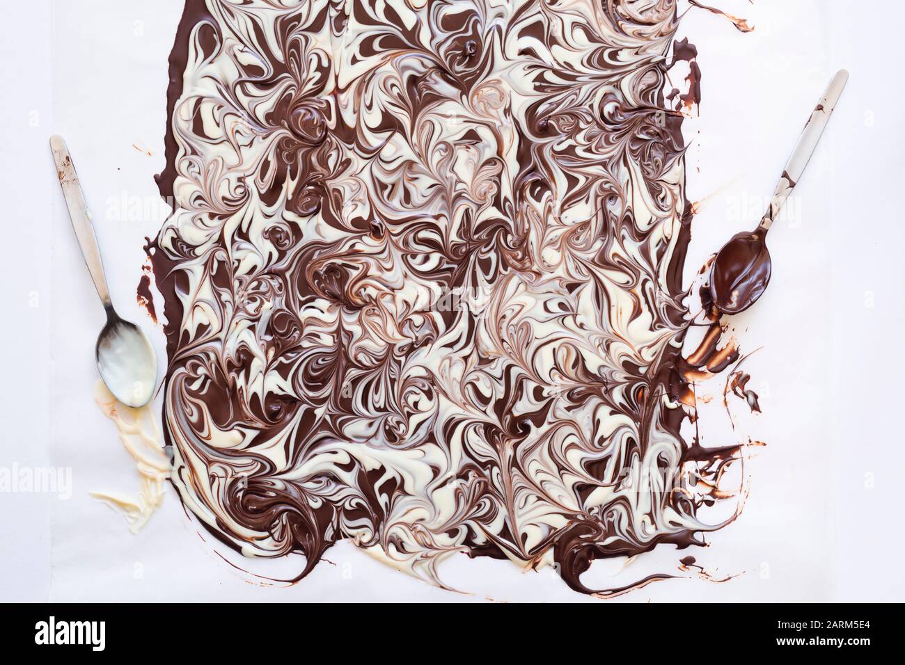 Chocolate marbling on a baking sheet with spoons Stock Photo