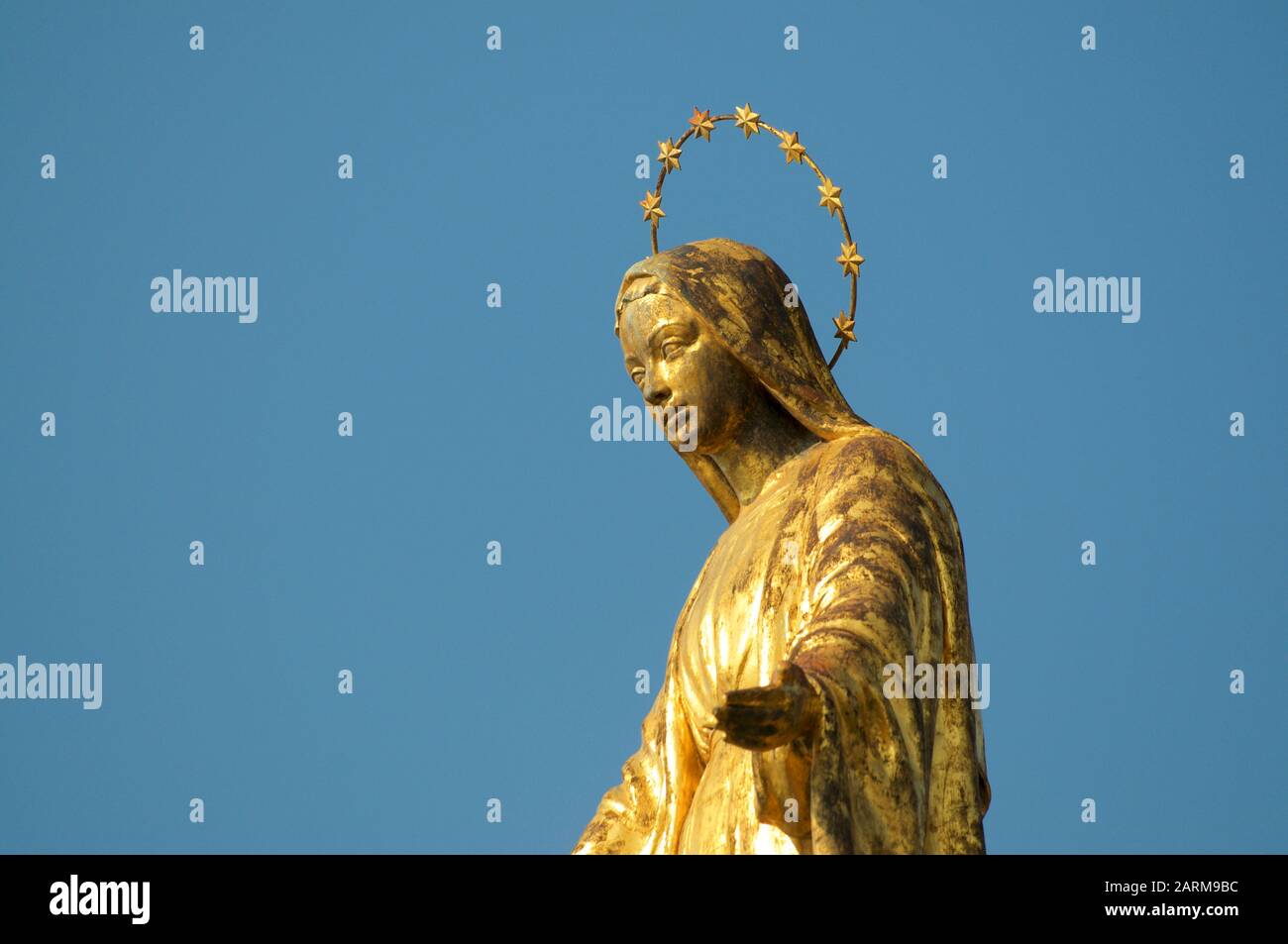 Close up view of the golden Madonnina (Madonna - Immacolata) statue against the blue sky located at the port of Luino in Lombardy, Italy Stock Photo