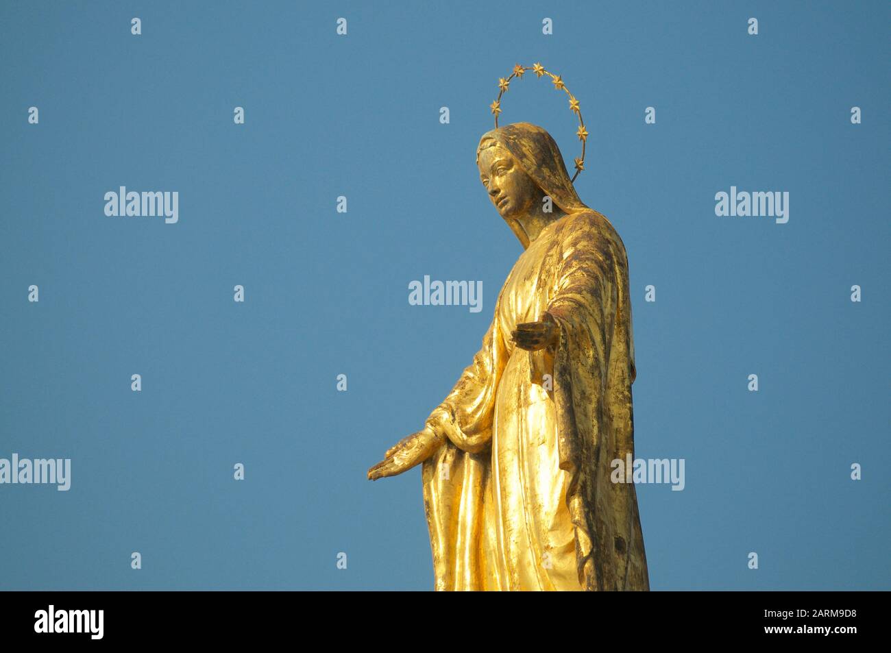 Close up view of the golden Madonnina (Madonna - Immacolata) statue against the blue sky located at the port of Luino in Lombardy, Italy Stock Photo