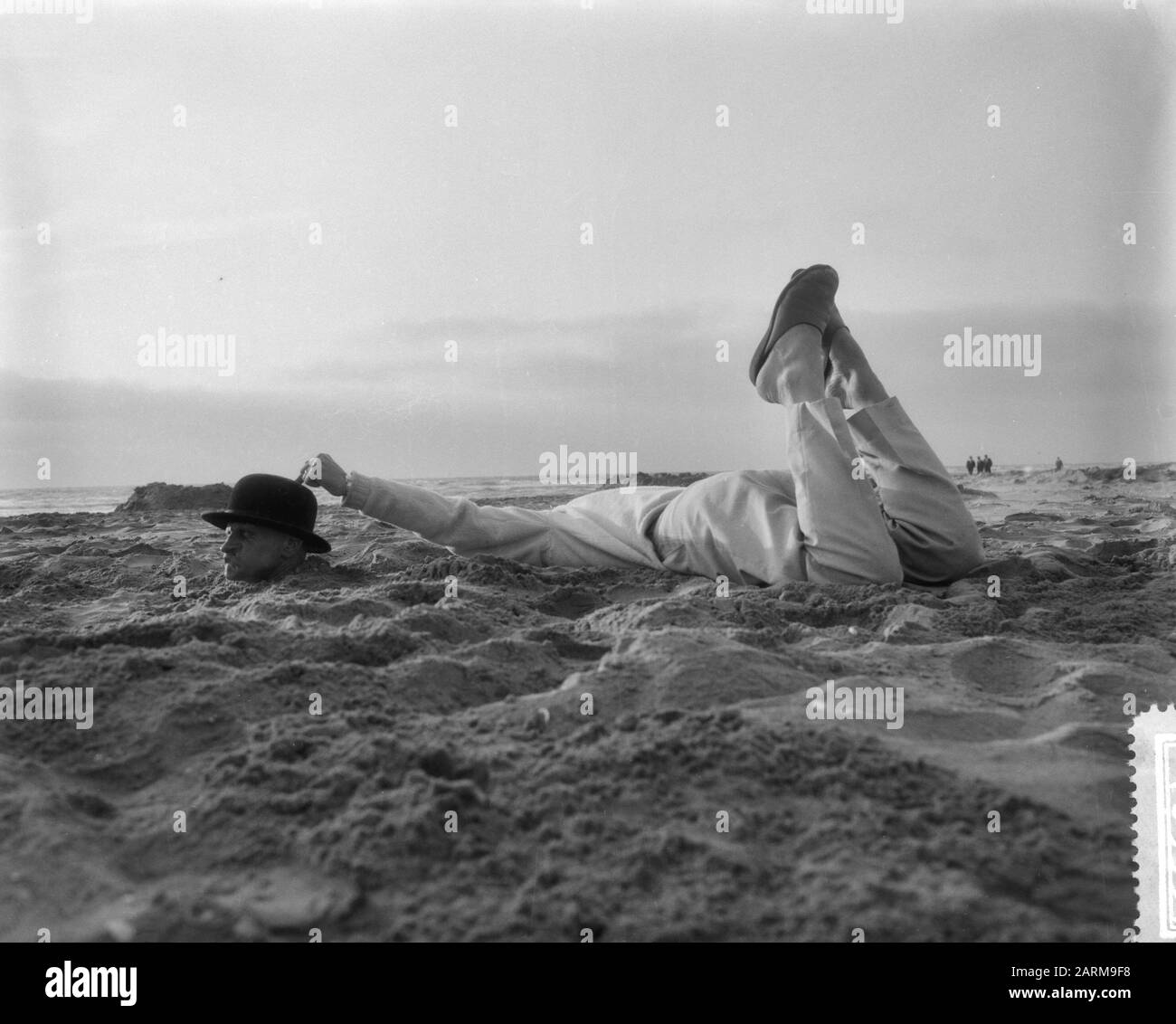Strange situation at the Dutch beach, man with whole body in the sand Date: May 25, 1959 Stock Photo