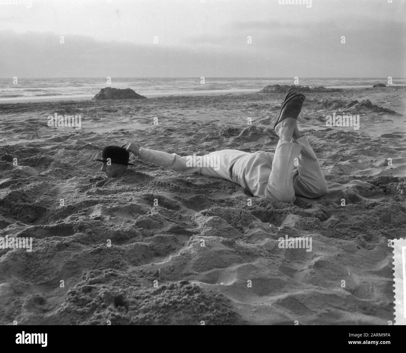 Strange situation at the Dutch beach, man with whole body in the sand Date: May 25, 1959 Stock Photo