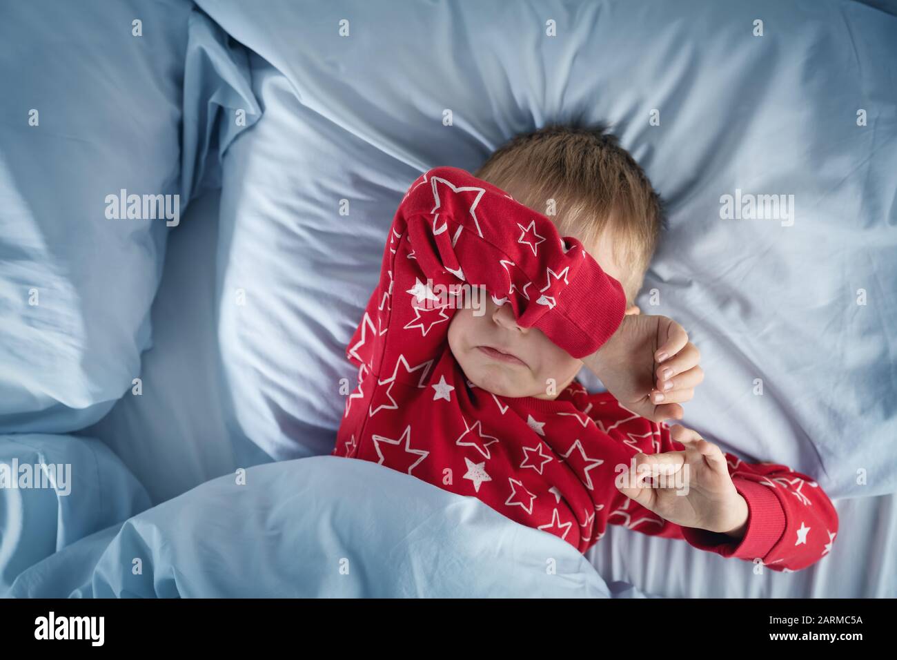 Sleepy boy lying in bed with blue beddings Stock Photo Alamy
