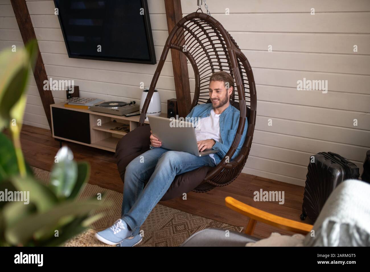 Smiling man sitting in the armchair working with a computer Stock Photo
