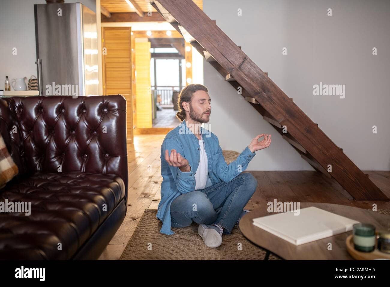 Relaxed young man meditating in his appartment Stock Photo