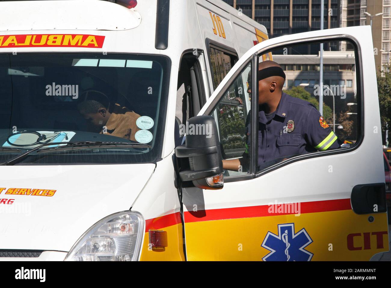 Ambulance, driver and medic parked on street with open door
