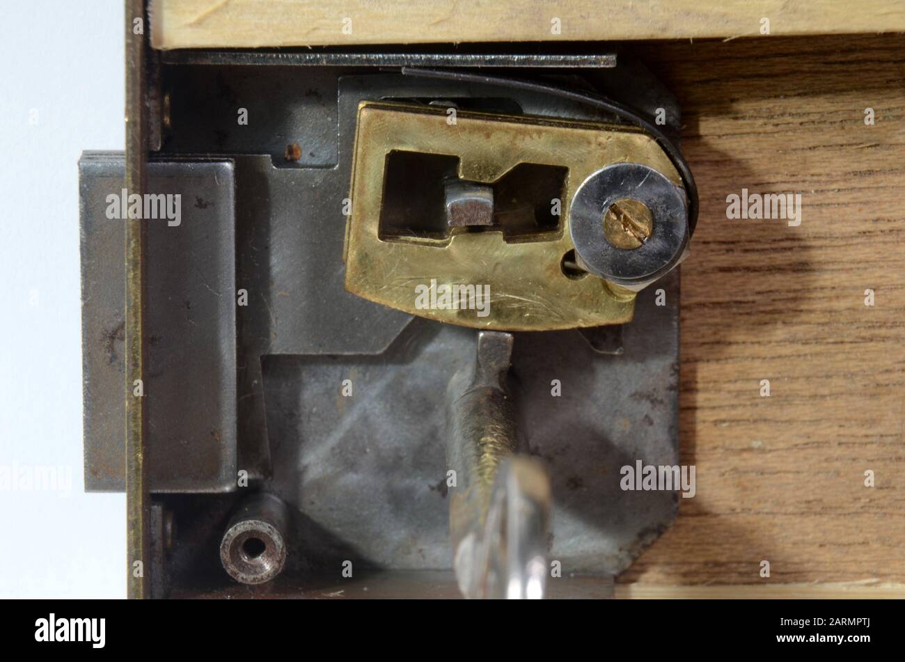 Closeup into a lock mechanism of a lever tumbler lock (front cover removed). This key fits, and the tumblers allow the opening of the lock. Stock Photo