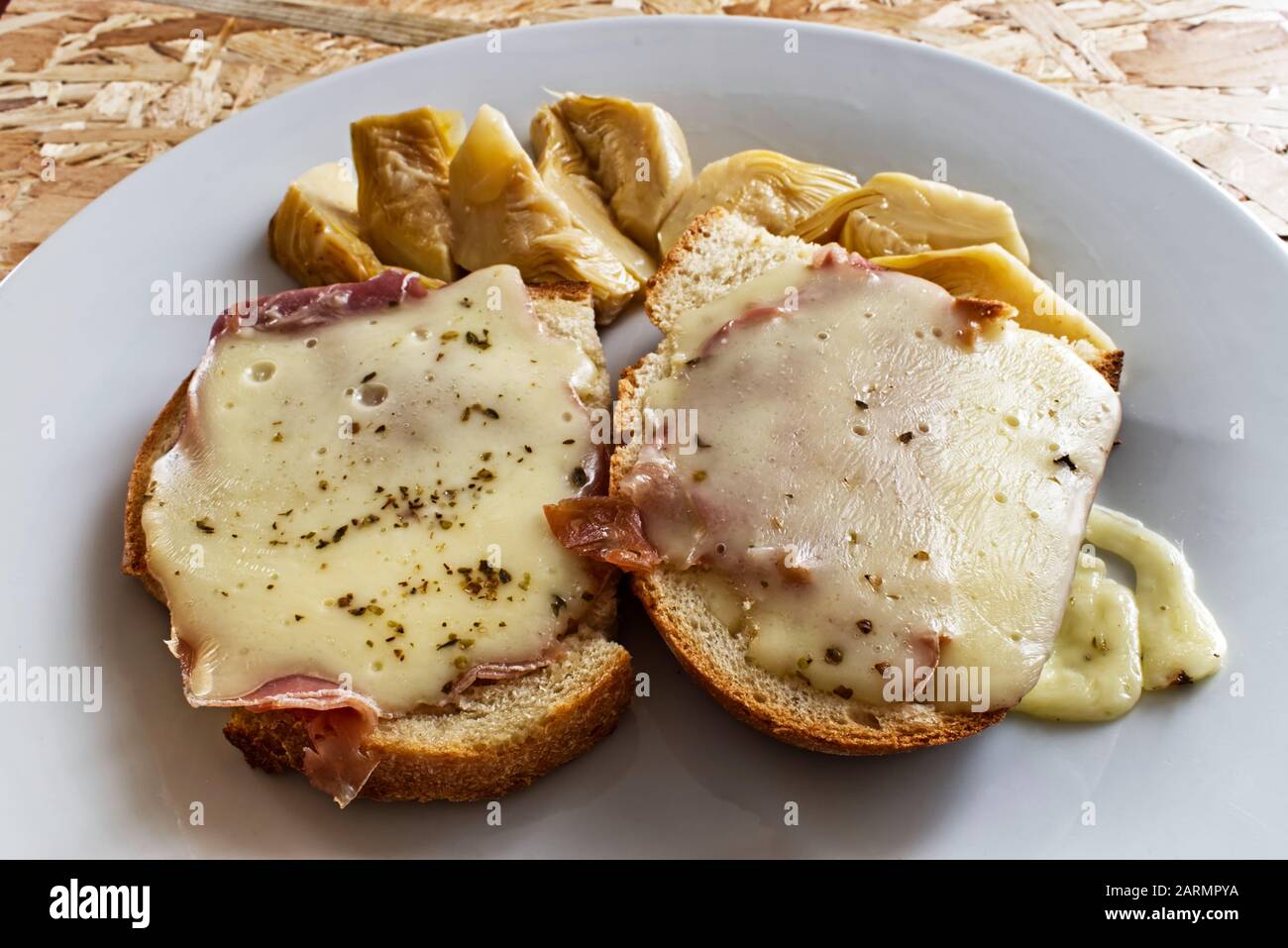 Bruschetta with cheese, ham, origan, olive oil. Artichoke salad. Stock Photo