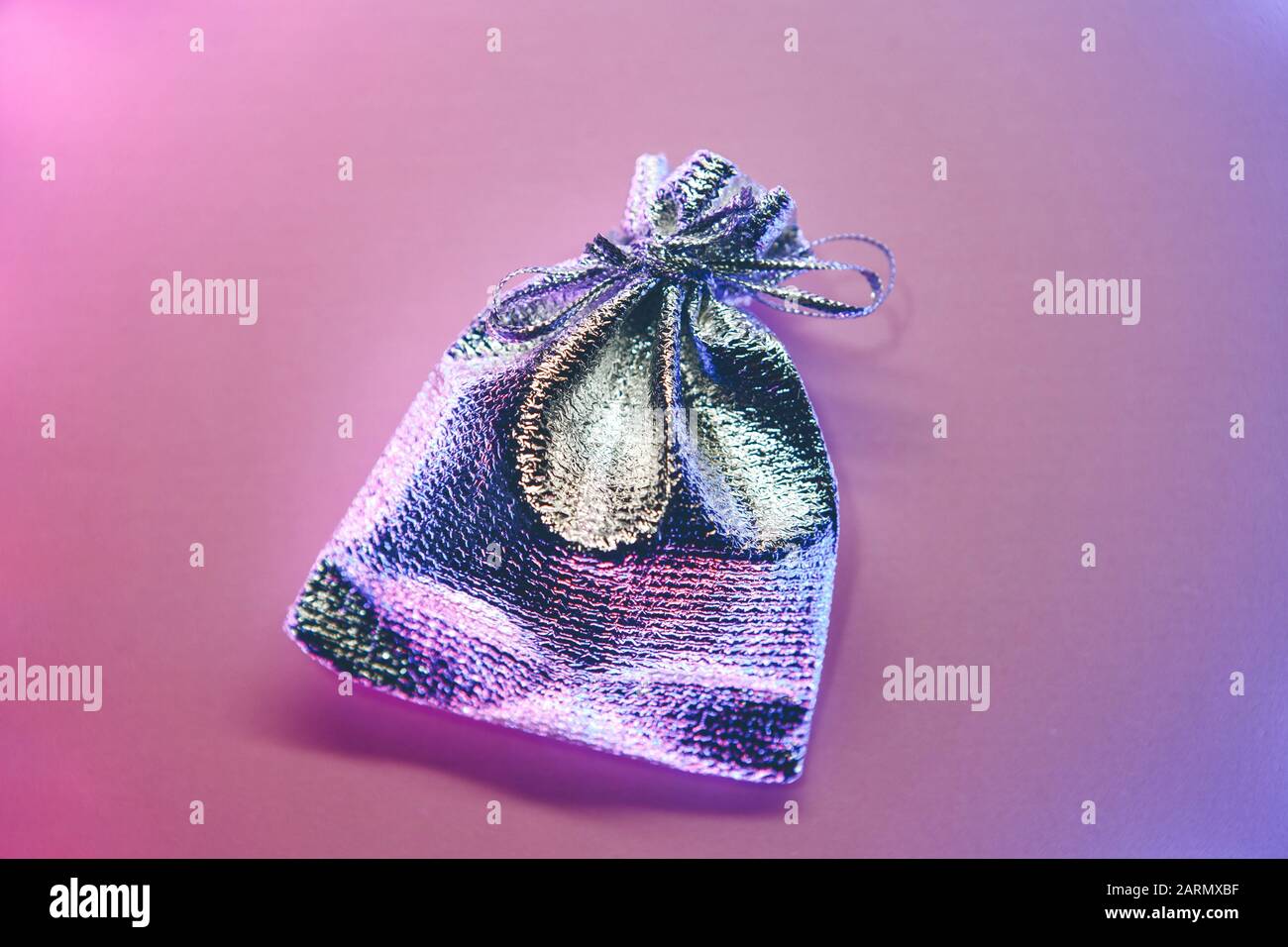 Silver small gift bag on a gradient background illuminated by neon